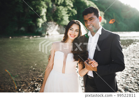 Wedding couple, groom and bride hugging, outdoor near river 99522811