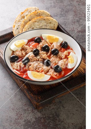 Murcian salad or mojete, a traditional fresh and light recipe that is prepared with tomato, canned tuna, black olive, egg and onion closeup on the plate. Vertical 99523401