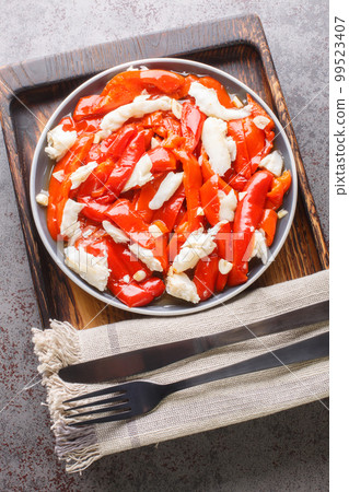Esgarraet valenciano or esgarrat is a typical dish of Spanish cuisine made of cod fish, bell peppers and garlic closeup on the plate. Vertical top view Esgarraet valenciano or esgarrat is a typical dish of Spanish cuisine made of cod fish, bell peppers and garlic closeup on the plate. Vertical top view 99523407