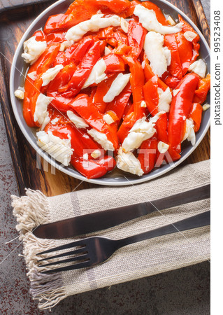 Tasty Esgarraet is a traditional Spanish dish that is made with red peppers, cod, and olive oil closeup on the plate. Vertical top view Tasty Esgarraet is a traditional Spanish dish that is made with red peppers, cod, and olive oil closeup on the plate. Vertical top view 99523408