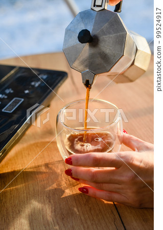Girl pours freshly brewed coffee into a transparent cup Girl pours freshly brewed coffee into a transparent cup 99524917