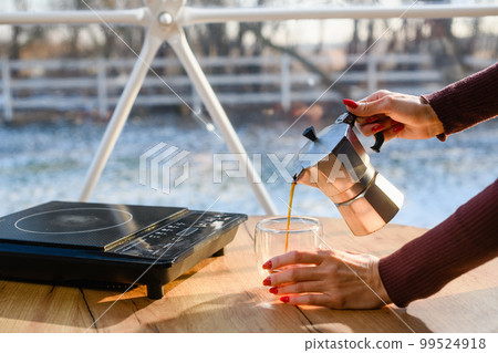 Girl pours freshly brewed coffee into a transparent cup 99524918
