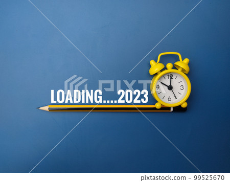 Pencil and alarm clock with the word LOADING 2023 on blue background. Pencil and alarm clock with the word LOADING 2023 on blue background. 99525670