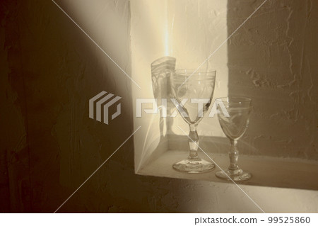 Light and shadow of the aperitif glass and crown ornament Light and shadow of the glass and jewel-encrusted crown ornament Light and shadow of the aperitif glass and crown ornament Light and shadow of the glass and jewel-encrusted crown ornament 99525860