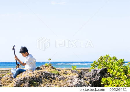 Okinawa Sanshin playing while feeling the sea breeze Okinawa Sanshin playing while feeling the sea breeze 99526481