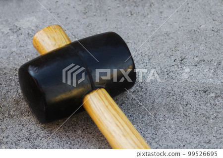 Defocus paving hammer close up. Garden brick pathway. Laying gray concrete paving slabs in courtyard on sand foundation base. Nobody. Out of focus Defocus paving hammer close up. Garden brick pathway. Laying gray concrete paving slabs in courtyard on sand foundation base. Nobody. Out of focus 99526695