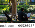 A man who puts down his bike and plays guitar in the park 99526987