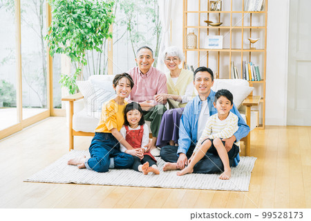 Three-generation family relaxing in the living room 99528173