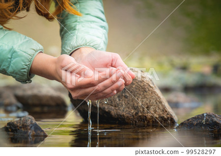 Hands and water. Close-up of a woman taking water from a mountain lake in her hands Hands and water. Close-up of a woman taking water from a mountain lake in her hands 99528297