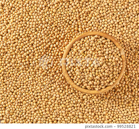 wooden plate with soybeans on a soybeans background close-up top view. wooden plate with soybeans on a soybeans background close-up top view. 99528821