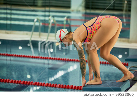 Diving into water. Professional female swimmer training in swimming pool indoor. Start of training session. Concept of sport, endurance, competition 99528860