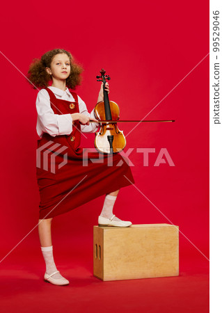 Portrait of little girl, talanted musician wearing huge mother's sundress posing with violin isolated over magenta background. Education, music, classic art, new vision, fun concept Portrait of little girl, talanted musician wearing huge mother's sundress posing with violin isolated over magenta background. Education, music, classic art, new vision, fun concept 99529046