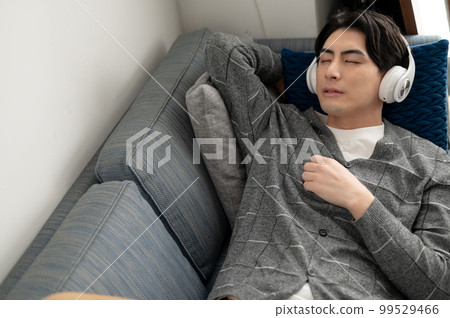 A man sleeping on the sofa while listening to music A man sleeping on the sofa while listening to music 99529466