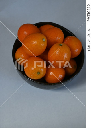 Kumquats piled high in a black bowl Kumquats piled high in a black bowl 99530310