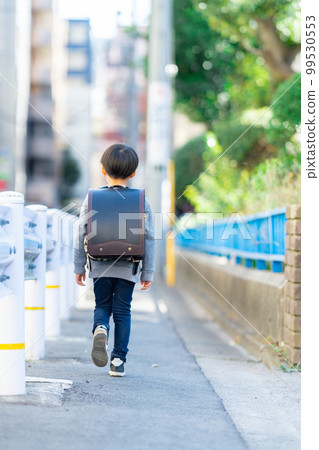 A boy walking with a school bag A boy walking with a school bag 99530553