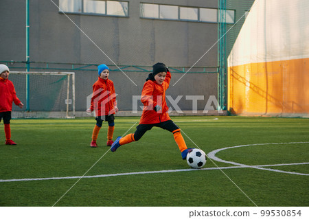 Position on field. Boy, child, playing football, training on sports field outdoor. Running with ball, dribbling. Concept of sport, childhood, active lifestyle 99530854