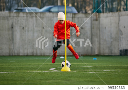 Coordinated movements. Little boy, child, football player in uniform training outdoor at sports stadium. Dribbling ball. Concept of sport, childhood, active lifestyle 99530883