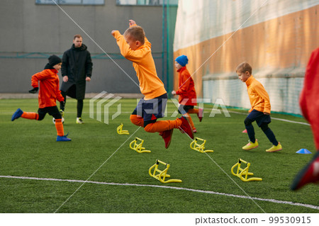 Boys, children, football players doing exercises, warming up before training session with coach on sports field outdoors. Concept of sport, childhood, active lifestyle 99530915
