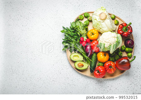 Rustic wooden tray with selection of fresh vegetables and greenery on white kitchen table top view. Vegetarian and diet food from organic ingredients, healthy nutrition concept, space for text 99532015