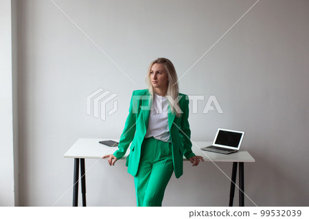 A woman in a green suit on white wall background. A woman in a green suit on white wall background. 99532039