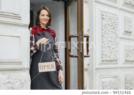 happy woman with sign open in her hands at restaurant or bar. working hours of coffee shop happy woman with sign open in her hands at restaurant or bar. working hours of coffee shop 99532488