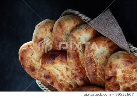 Bread in the form of tortillas. Bread cakes made from wheat flour. Bread in a basket on a dark background. He was lying flat. View from above. 99532607