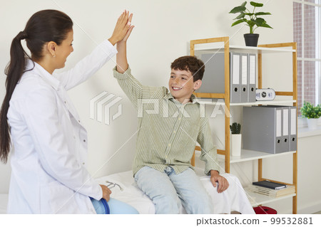 Happy teen boy patient giving five to woman pediatrician in medical uniform during visit in clinic. Happy teen boy patient giving five to woman pediatrician in medical uniform during visit in clinic. 99532881