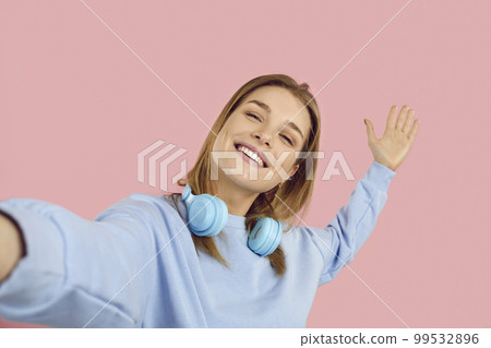 Happy beautiful young woman smiling and taking selfie on camera of her mobile phone 99532896