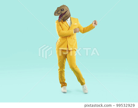 Funny crazy man wearing dinosaur mask dancing at party 99532929