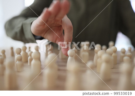 The hand pushes wooden figures of men on the table 99533019