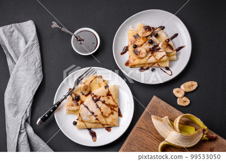 Delicious fresh baked pancakes with honey and fruits on a concrete background Delicious fresh baked pancakes with honey and fruits on a concrete background 99533050