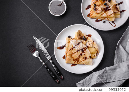 Delicious fresh baked pancakes with honey and fruits on a concrete background Delicious fresh baked pancakes with honey and fruits on a concrete background 99533052