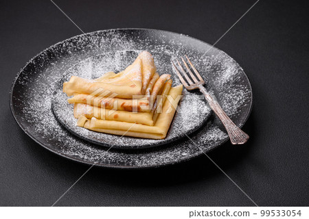 Delicious fresh baked pancakes with honey and fruits on a concrete background Delicious fresh baked pancakes with honey and fruits on a concrete background 99533054