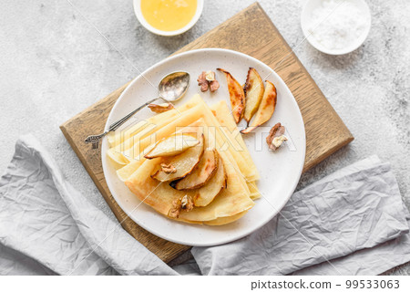 Delicious fresh baked pancakes with honey and fruits on a concrete background Delicious fresh baked pancakes with honey and fruits on a concrete background 99533063