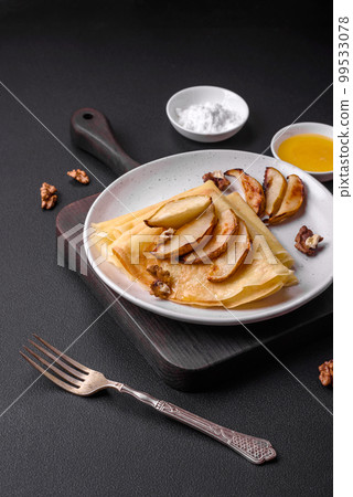 Delicious fresh baked pancakes with honey and fruits on a concrete background 99533078