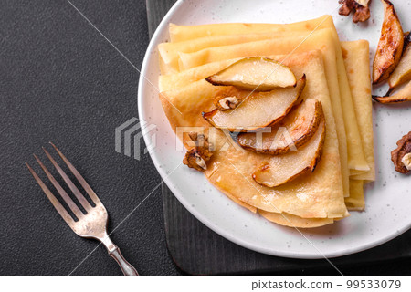 Delicious fresh baked pancakes with honey and fruits on a concrete background Delicious fresh baked pancakes with honey and fruits on a concrete background 99533079