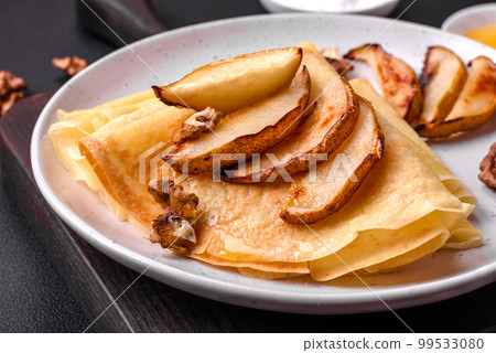 Delicious fresh baked pancakes with honey and fruits on a concrete background Delicious fresh baked pancakes with honey and fruits on a concrete background 99533080