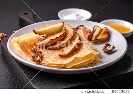 Delicious fresh baked pancakes with honey and fruits on a concrete background Delicious fresh baked pancakes with honey and fruits on a concrete background 99533081
