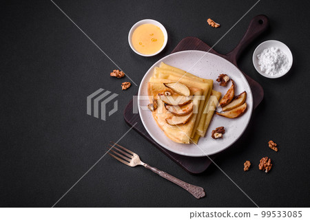 Delicious fresh baked pancakes with honey and fruits on a concrete background Delicious fresh baked pancakes with honey and fruits on a concrete background 99533085