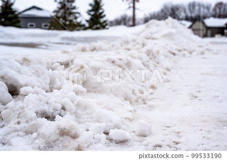 Snowbank at the end of a driveway left after city snowplows cleared a street. Snowbank at the end of a driveway left after city snowplows cleared a street. 99533190
