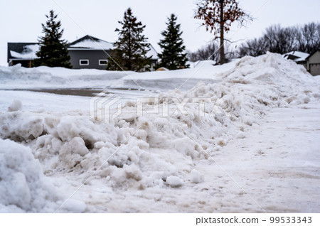 Snowbank at the end of a driveway left after city snowplows cleared a street. Snowbank at the end of a driveway left after city snowplows cleared a street. 99533343