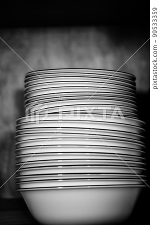 Narrow depth of field picture of an open kitchen cabinet stacked ceramic plates and bowls. Narrow depth of field picture of an open kitchen cabinet stacked ceramic plates and bowls. 99533359