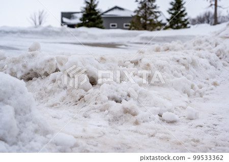 Snowbank at the end of a driveway left after city snowplows cleared a street. Snowbank at the end of a driveway left after city snowplows cleared a street. 99533362