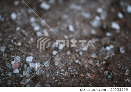 macro ground level closeup view of rock salt ice-melt on concrete with a frozen layer. macro ground level closeup view of rock salt ice-melt on concrete with a frozen layer. 99533369