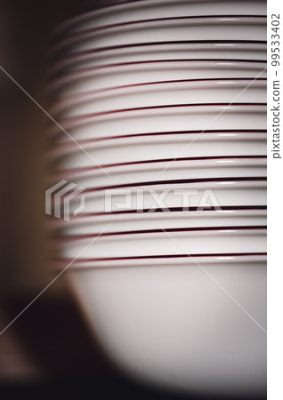 Narrow depth of field picture of an open kitchen cabinet stacked ceramic plates and bowls. Narrow depth of field picture of an open kitchen cabinet stacked ceramic plates and bowls. 99533402