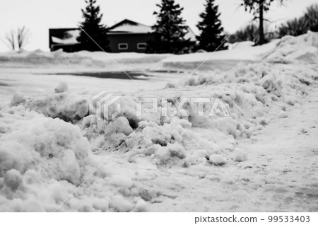 Snowbank at the end of a driveway left after city snowplows cleared a street. Snowbank at the end of a driveway left after city snowplows cleared a street. 99533403