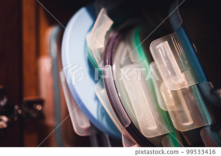 Narrow depth of field picture of an open kitchen cabinet with an assortment of containers and mismatched lids stacked. Narrow depth of field picture of an open kitchen cabinet with an assortment of containers and mismatched lids stacked. 99533416