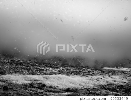 Blowing snow and Focus stacked ground level view of ice accumulation on a sidewalk with blowing snow.  99533449