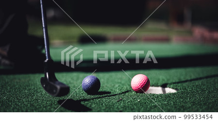 Mini golf game with several colored balls in the way of a putter lined up. Mini golf game with several colored balls in the way of a putter lined up. 99533454