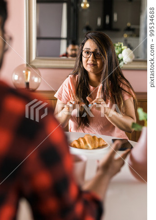 Young diverse loving couple eating croissant and talks together at home in breakfast time. Communication and relationship concept 99534688